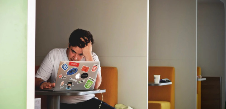 A depressed man looking at mac book